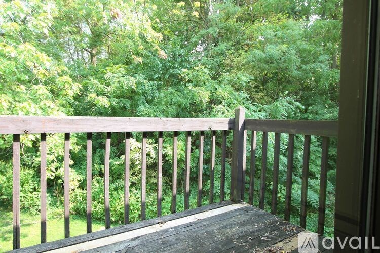 A wooden balcony overlooks a lush green forest.