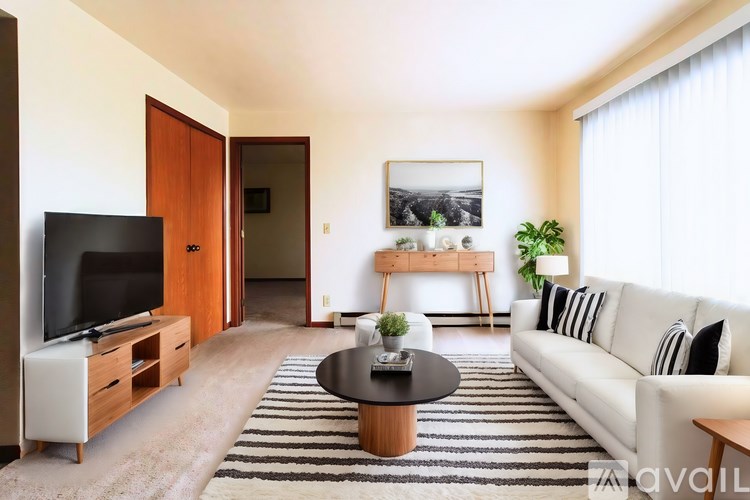 A living room with a white couch, a coffee table, and a television.