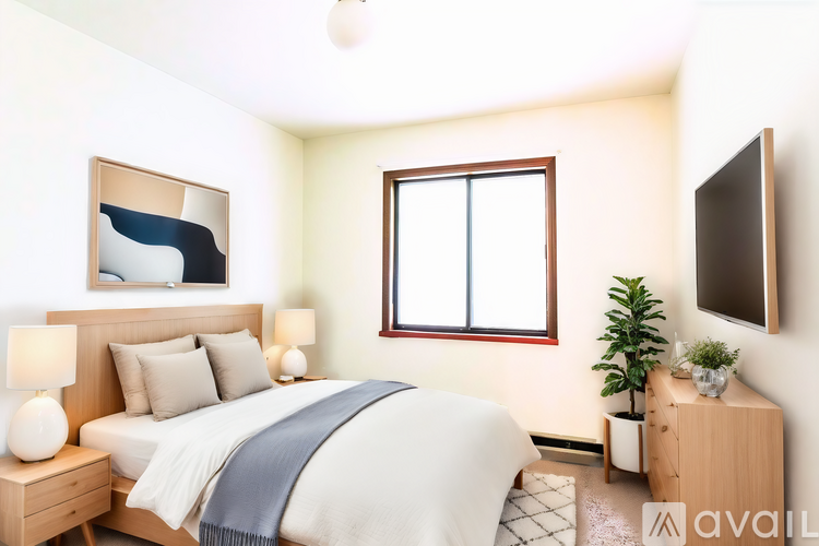 A well-lit bedroom with a bed, nightstand, and a window.