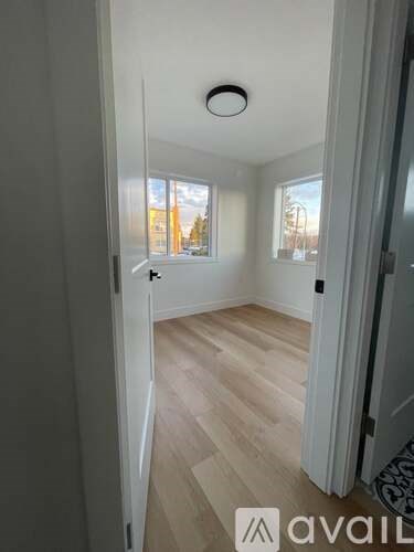 A room with wooden flooring and a window showing trees outside.