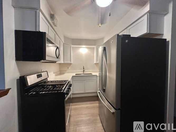 A kitchen with a refrigerator, sink, and cabinets.