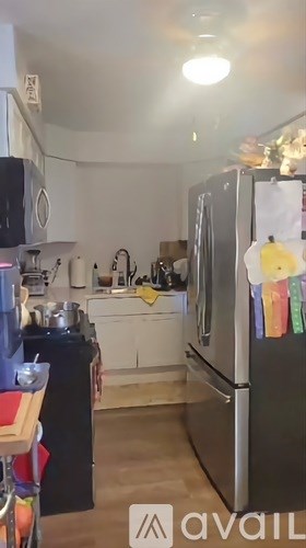 A kitchen with a refrigerator, sink, and cabinets.