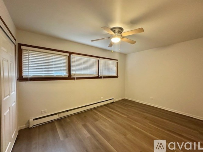 A room with a ceiling fan and wooden flooring.