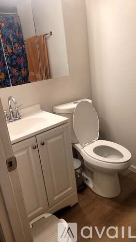 A white toilet is in a bathroom with a white sink and cabinet.