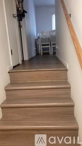 A staircase with a white wall on the side and a wooden banister.