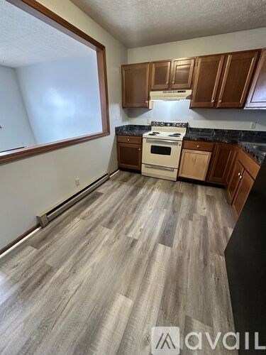 A kitchen with wooden cabinets and a white stove top oven.