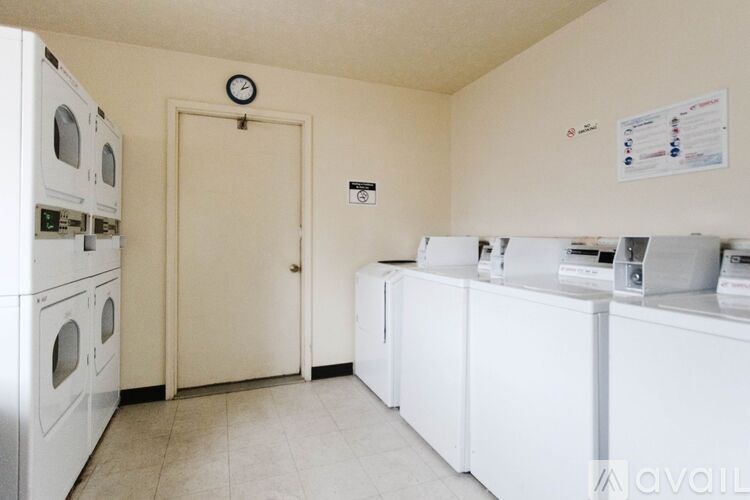 A laundry room with a clock on the wall and a washing machine on the left.