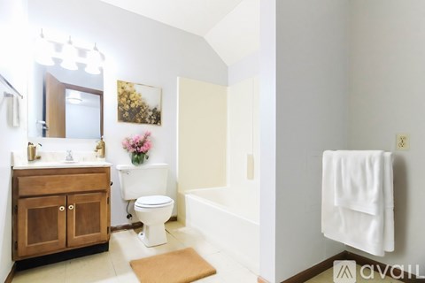 A white toilet sits in a bathroom next to a white bathtub.
