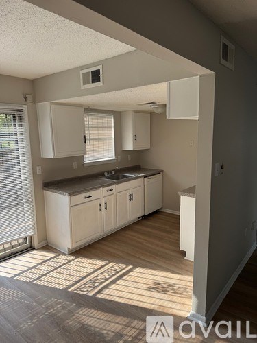 A kitchen with white cabinets and a window with blinds.