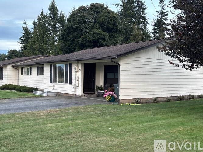 A house with a front yard and a tree in the background.