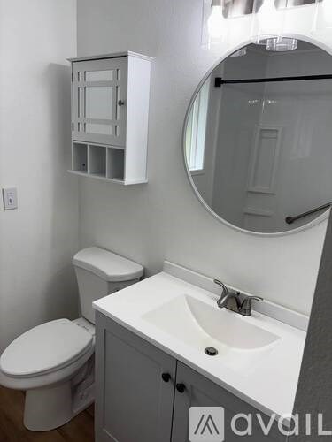 A bathroom with a toilet, sink and medicine cabinet.