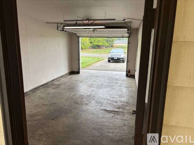 A car is parked in the driveway visible through the garage door.