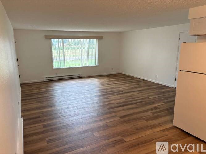 A room with wooden flooring and a window with blinds.
