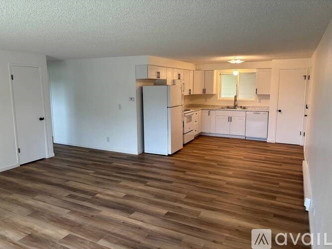 A kitchen with white cabinets and a wooden floor.