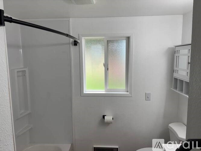 A bathroom with a toilet, sink, and window.