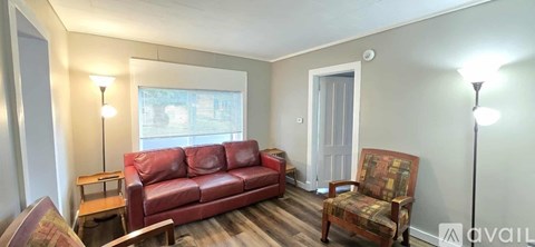 A living room with a red couch and a wooden chair.
