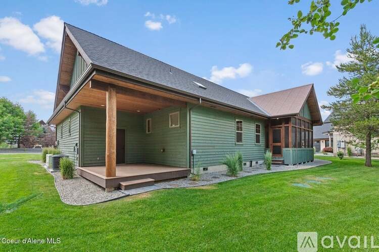 A house with a green siding and a brown roof is for sale.