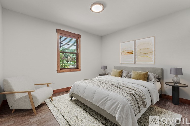 A bedroom with a large bed, a chair, and a window.