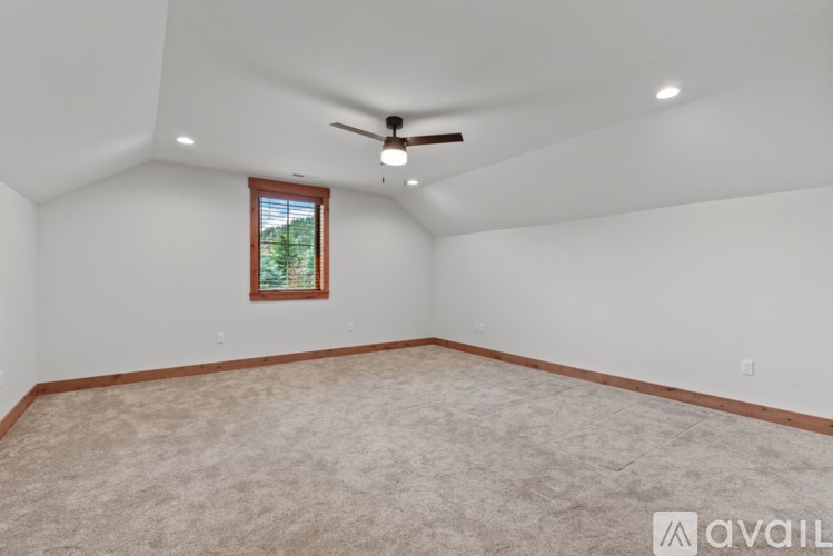 A room with a ceiling fan and a window with a view of trees.