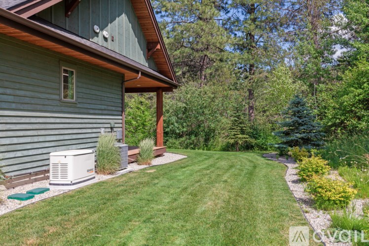 A house with a green lawn and trees in the background.