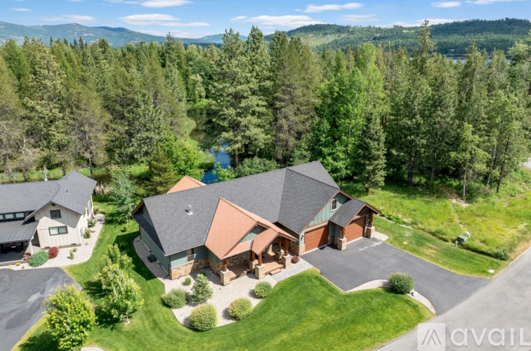 A house with a brown roof is surrounded by greenery and trees.