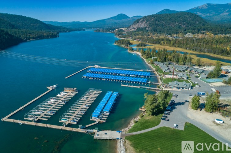 A marina with boats docked in the water and a mountain range in the background.