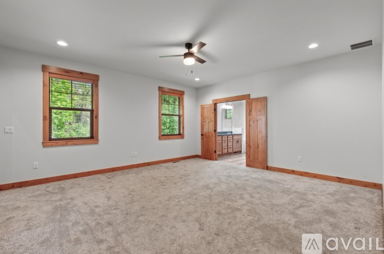 A spacious room with a ceiling fan and two windows.