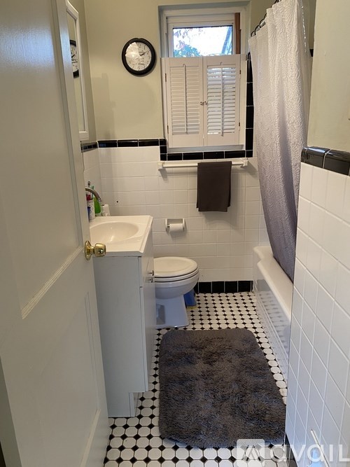 A small bathroom with a toilet, sink, and a black and white floor.