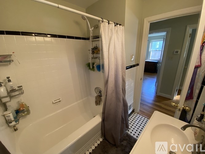 A bathroom with a white tub, a shower curtain, and a sink.