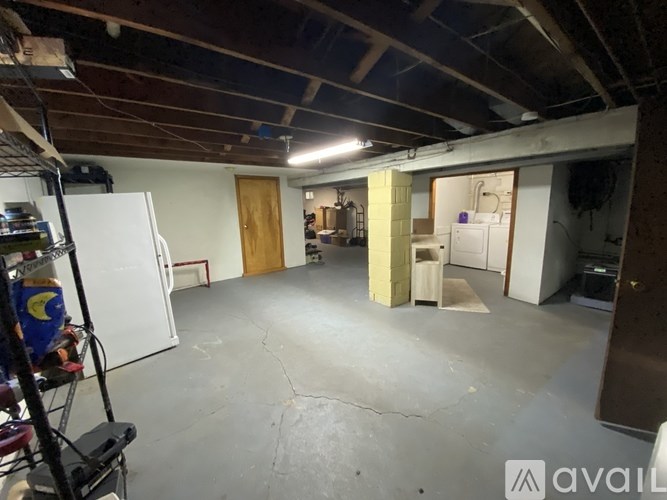 A room with a white fridge and a wooden door.