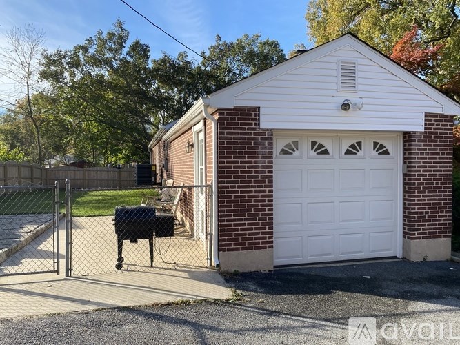 A white garage with a black mailbox and a white door is surrounded by a brick wall and a fence.