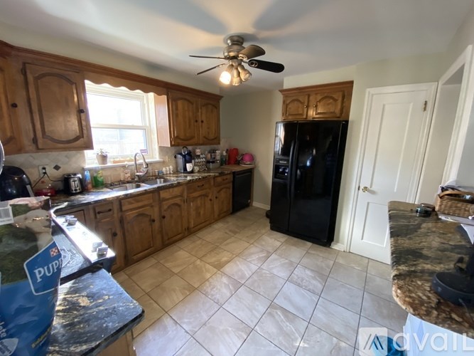 A kitchen with a black fridge and a fan on the ceiling.