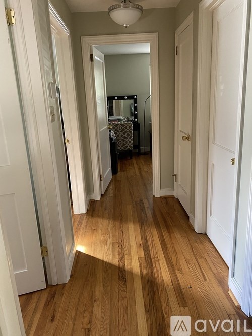A long hallway with white doors and wood floors.