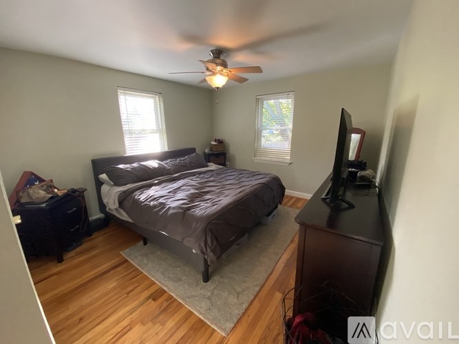 A bedroom with a bed, dresser, and a ceiling fan.