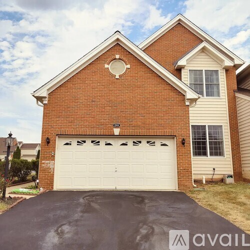 A brick house with a white garage door and a driveway.
