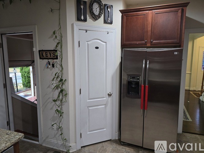 A kitchen with a white door, a clock, and a plant.