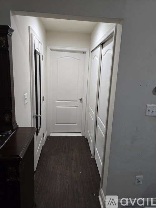 A hallway with a white door and a brown piano.