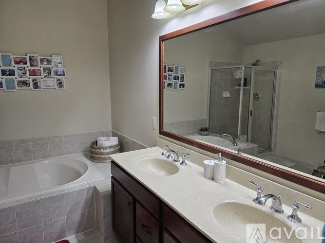A bathroom with a white tub, two sinks, and a mirror.