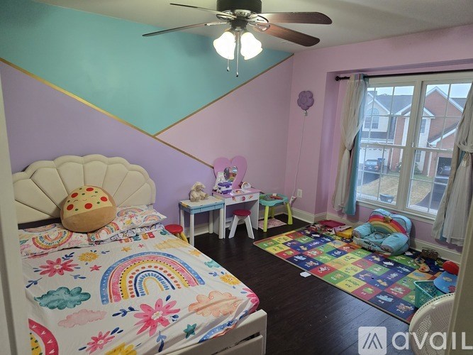 A bedroom with a bed, a ceiling fan, and a rainbow-patterned bedspread.
