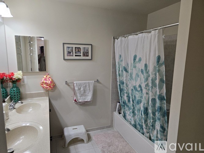 A bathroom with a white sink, a towel hanging on the wall, and a shower curtain with blue and green patterns.
