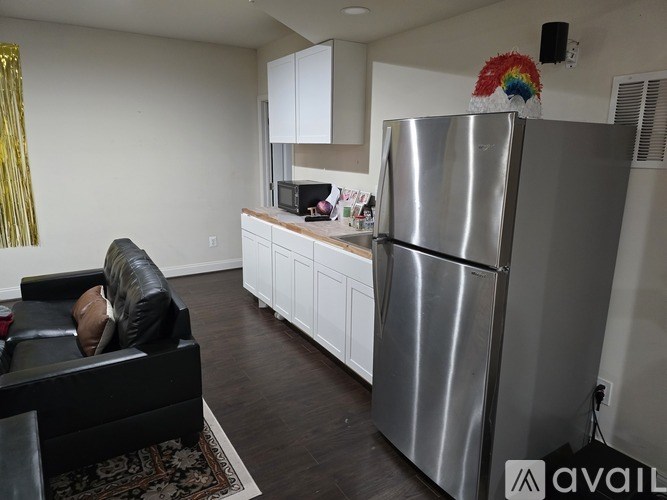 A kitchen with a refrigerator and a couch.