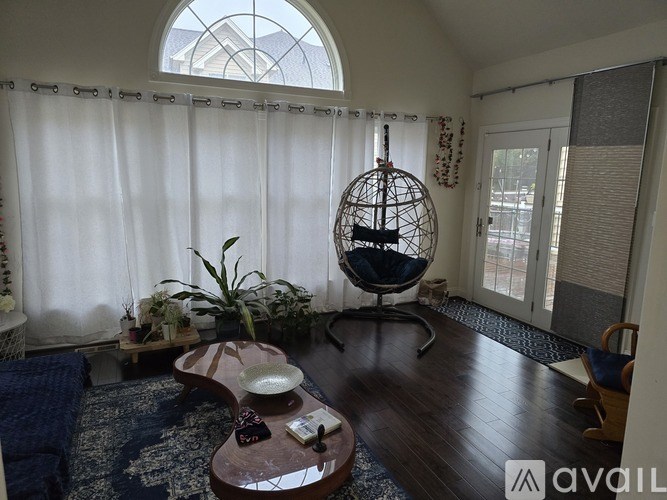 A living room with a blue rug and a white curtain.
