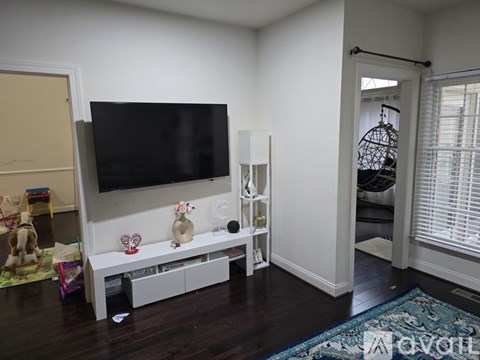 A living room with a television and a white shelf.