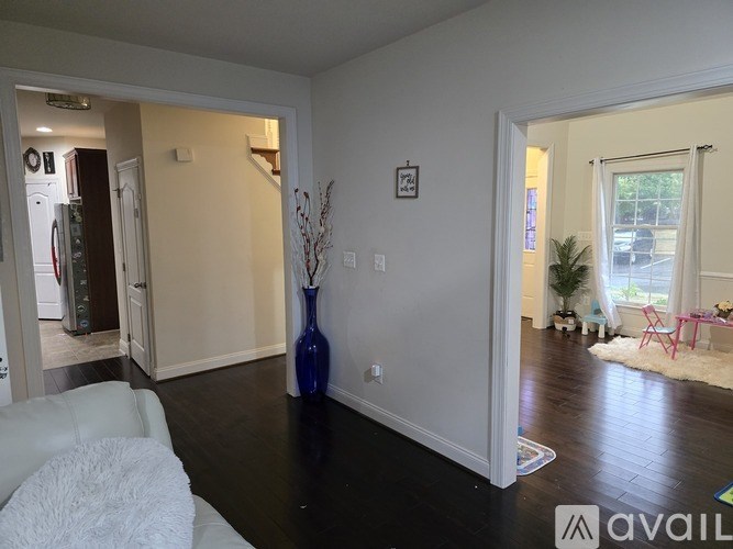 A living room with a white couch and a blue vase.