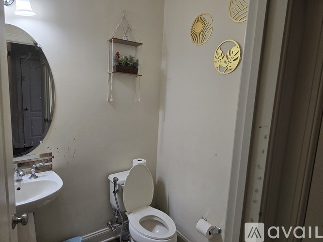 A bathroom with a toilet, sink, and decorative wall hangings.