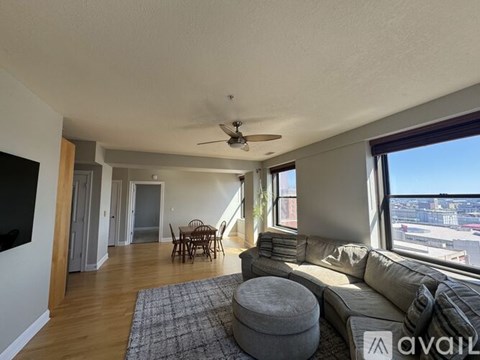 A living room with a grey couch and a ceiling fan.
