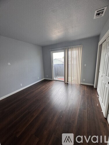A room with wooden floors and a door leading to a balcony.