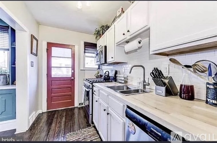 A kitchen with a red door and white cabinets.