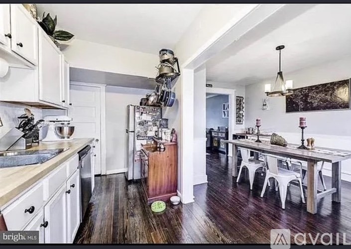 A kitchen with white cabinets and a wooden floor.