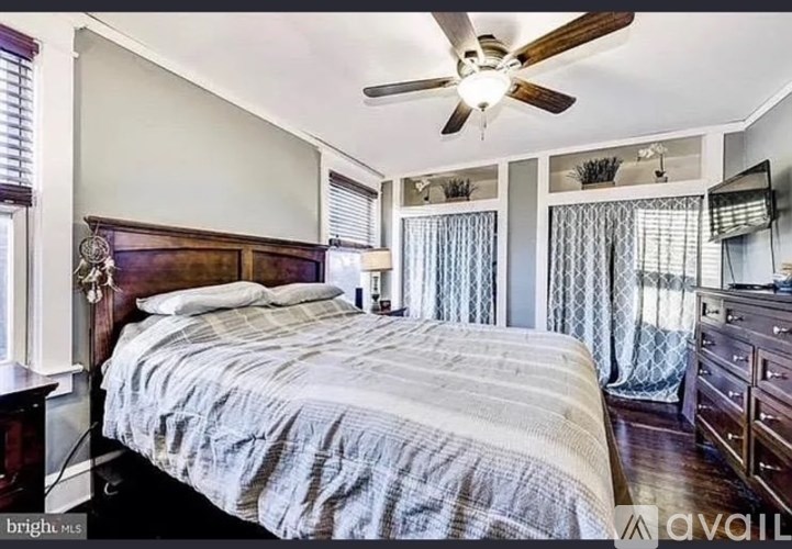 A bedroom with a bed, dresser, and ceiling fan.